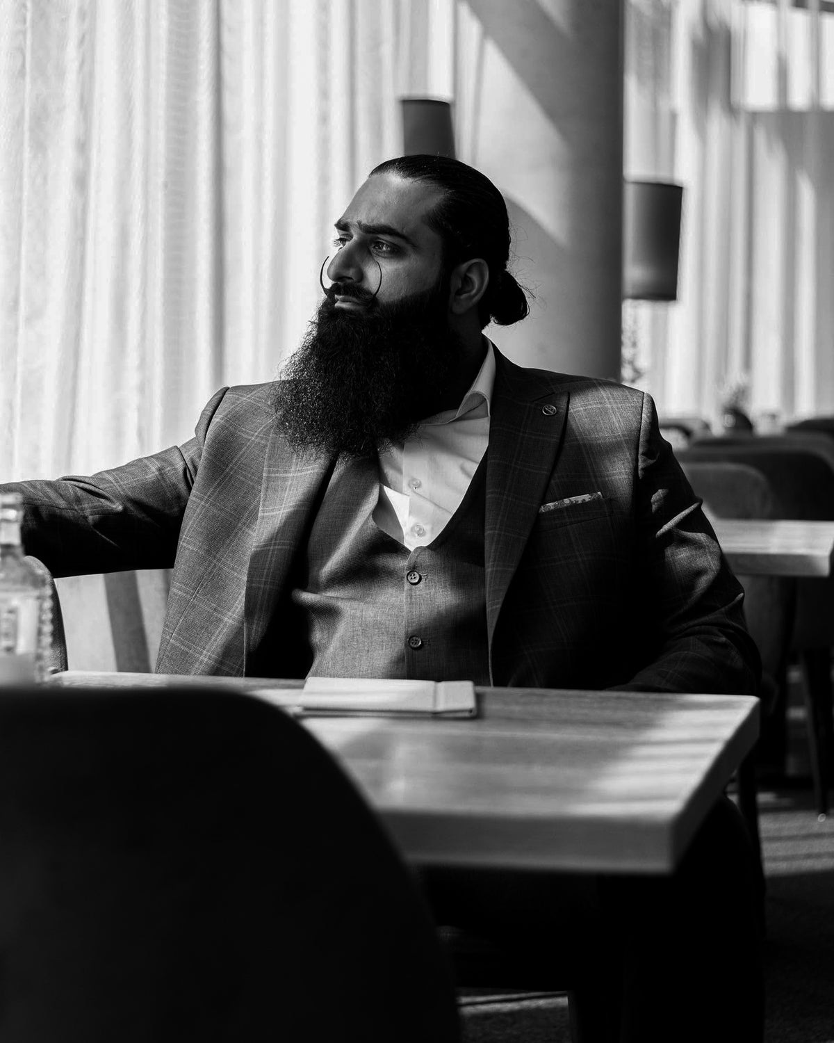 Naqash Mushtaq, digital creator, seated at a table in a suit